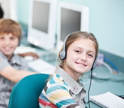 Elementary school girl in headphones on computer